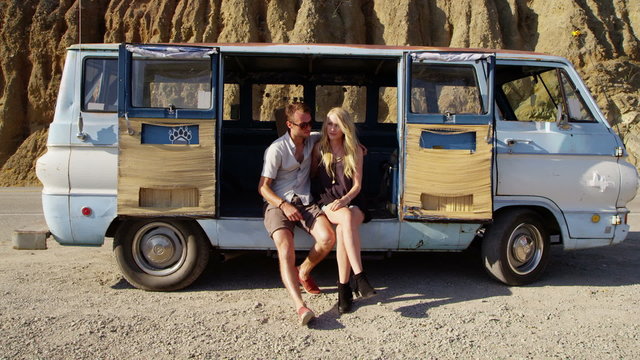Young couple sitting together by old van