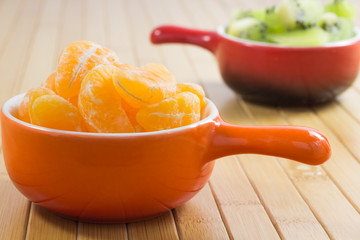 Tangerines peeled slices in an orange on a plate. In the backgro
