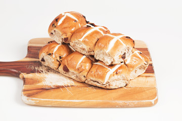Hot cross buns on a timber board with a white background.
