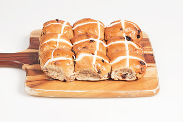 Hot cross buns on a timber board with a white background.