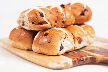 Hot cross buns on a timber board with a white background.