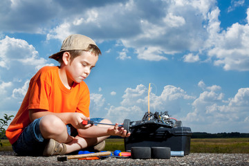 Little boy repaire the radio control car outdoor near field