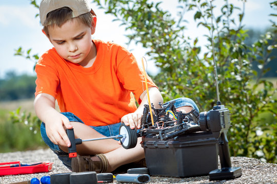 Little boy repaire the radio control car outdoor near field