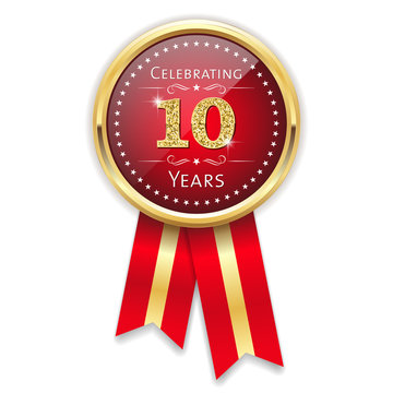 Red celebrating 10 years badge, rosette with gold border and ribbon