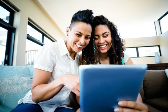 Lesbian couple sitting on sofa and using digital tablet - Powered by Adobe