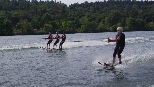 Three water skiers go off jump and one goes under