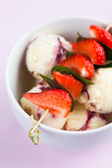 Vanilla ice cream with strawberries and mint leaves on a skewer