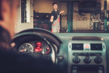 Professional car mechanic welcomes new client to his auto repair service.