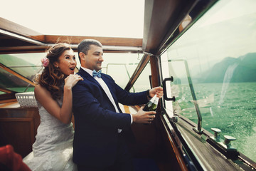 Cute happy stylish couple celebrating their marriage on a yacht,