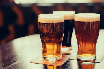 Gläser helles und dunkles Bier auf einem Pub-Hintergrund.