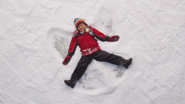 Young boy making snow angel in winter