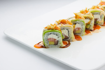 Sushi with avocado salmon and cheese. Crunch Roll. With delicious sauces. On a plate over white background.