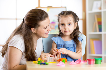 Mother and child daughter at home molded from clay and play together. Concept of preschool or home education.