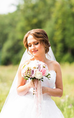 Beautiful bride girl in wedding dress  and bouquet of flowers, outdoors portrait