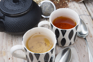 two cups 1 black tea rooibos and other fennel with teapot in the