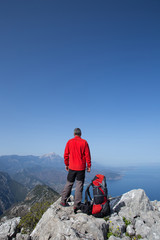 A traveler stands on top of a mountain and looks out to sea.