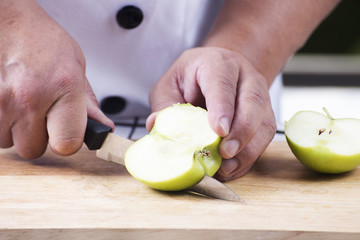 Chef's hands cutting green apple