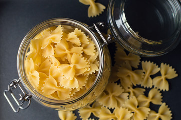 Uncooked italian pasta stored in a glass container, dark background