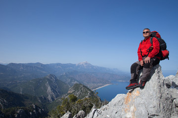 A traveler stands on top of a mountain and looks out to sea.