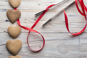 cookies and heart shaped red ribbon on the wooden background