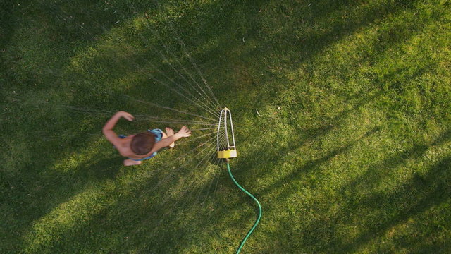 Child playing in sprinkler, overhead shot