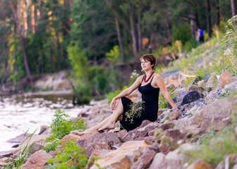 beautiful girl with flowers on the stoned river bank on forest b