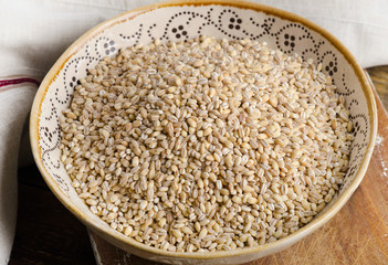 Barley in a ceramic bowl on  wooden board.