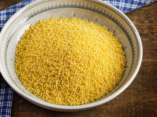 Organic millet in a bowl on wooden rustic table.