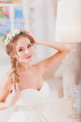 Beautiful bride blond girl in a wedding dress worn front of the mirror