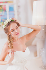 Beautiful bride blond girl in a wedding dress worn front of the mirror