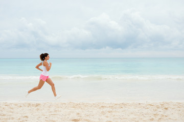 Fototapeta na wymiar Fitness woman running at the beach on summer vacation. Healthy female athlete training outdoor.