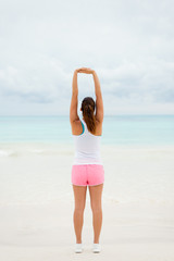 Back view of fitness woman doing stretching arms exercise for relaxing. Healthy lifestyle on summer vacation.