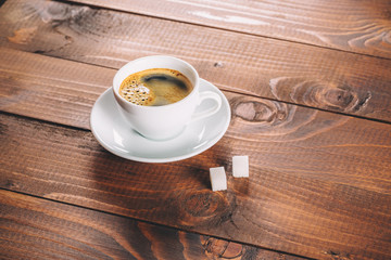 a beautiful Cup of coffee with two lumps of sugar cubes on old wooden background