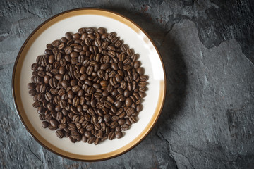 Coffee beans on the plate on the stone table top view
