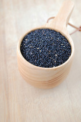 black sesames in a wooden cup on a bamboo board