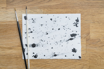 Blots of ink on a white paper on a wooden surface