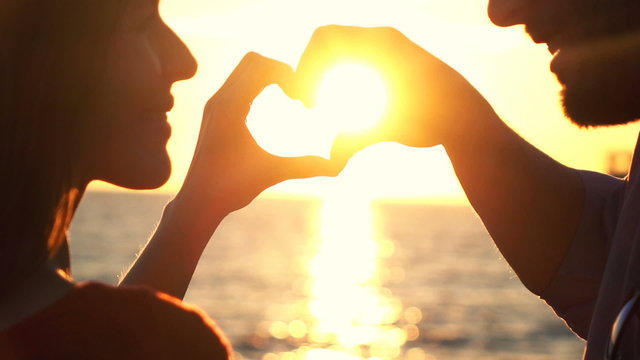 Couple making heart symbol with hands during sunset, super slow motion 240fps

