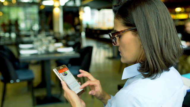 Businesswoman scrolling and zooming graphs on smartphone
