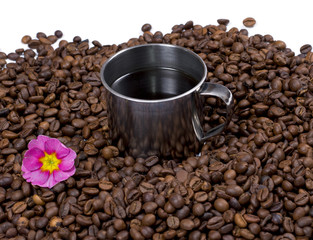 flower and steel cup of coffee in coffee grains