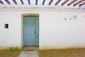 The image "ancient wooden door on a stone made wall and cement benches"