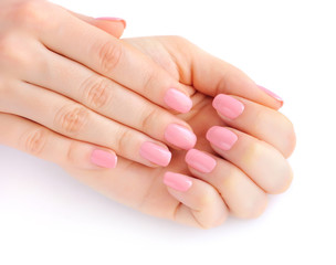 Closeup of hands of a young woman with pink manicure on nails against white background