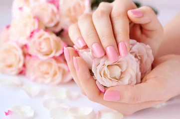 Abwaschbare Fototapete Maniküre Hände einer Frau mit rosa Maniküre auf Nägeln und Rosen