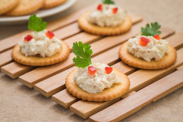 Crackers with tuna salad on wooden plate