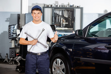 Naklejka premium Mechanic Gesturing Thumbs Up While Holding Rim Wrench