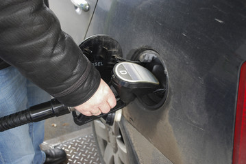 Filling a vehicle with fuel. Man's hand holding a gun to the fueling of the car.