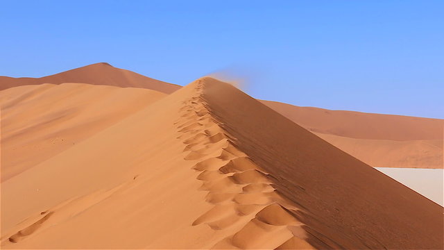 Zoom in moving over sanddune with sandstorm Sossusvlei Namibia Africa
