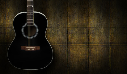 Fototapeta premium Black acoustic guitar on dark yello wooden background.