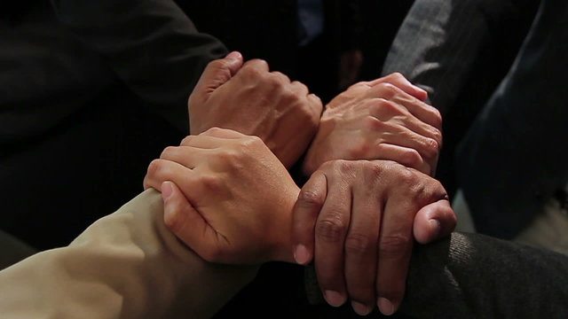 Joint hands of four businessmen, close shot