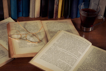 Открытые книги на столе, очки и кружка