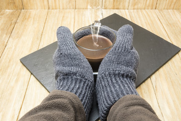 man hands with gloves warming up with a cup of cocoa
